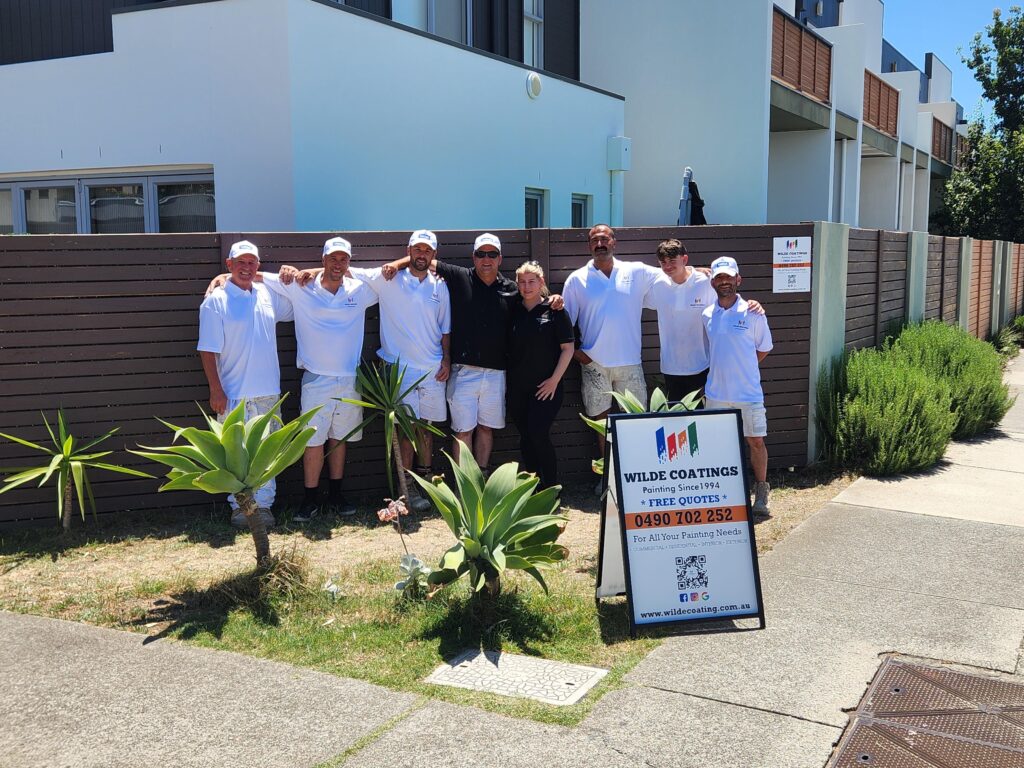 team photo in front of painted houses